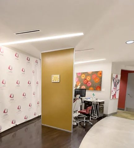 Interior hallway beside a Lowe Orthodontics logo backdrop and a treatment station