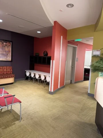 Waiting area with colorful chairs and a counter with stools